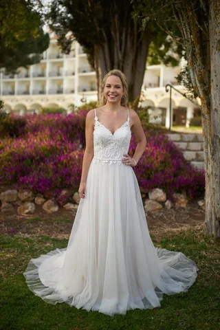 Braut in einem fließenden Brautkleid mit Schleppe in einer Gartenkulisse
