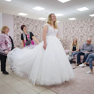Braut präsentiert ein voluminöses Kleid vor ihren Begleitungen