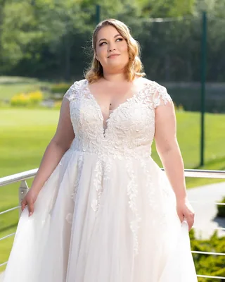 Plus-Size-Braut in einem Spitzenkleid im Grünen